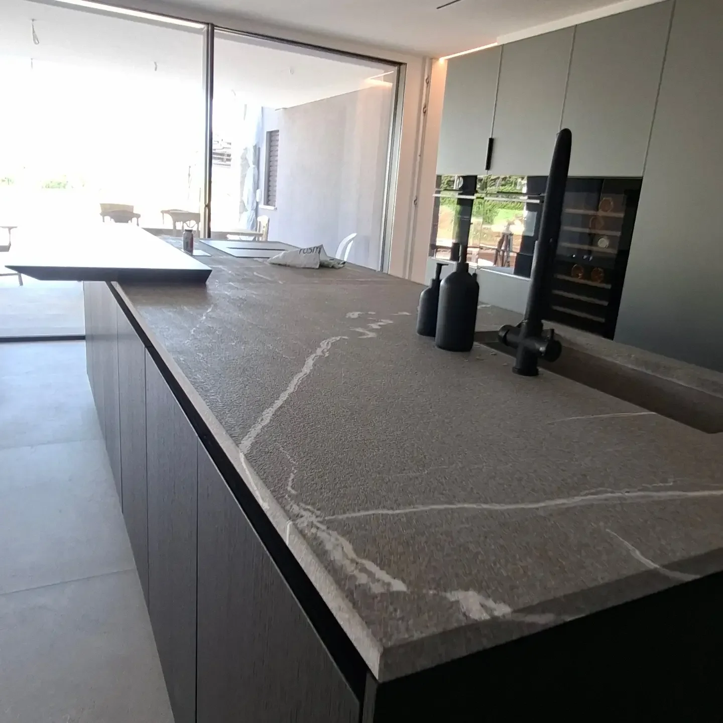 Isola della cucina con piano in pietra venata e rubinetto nero