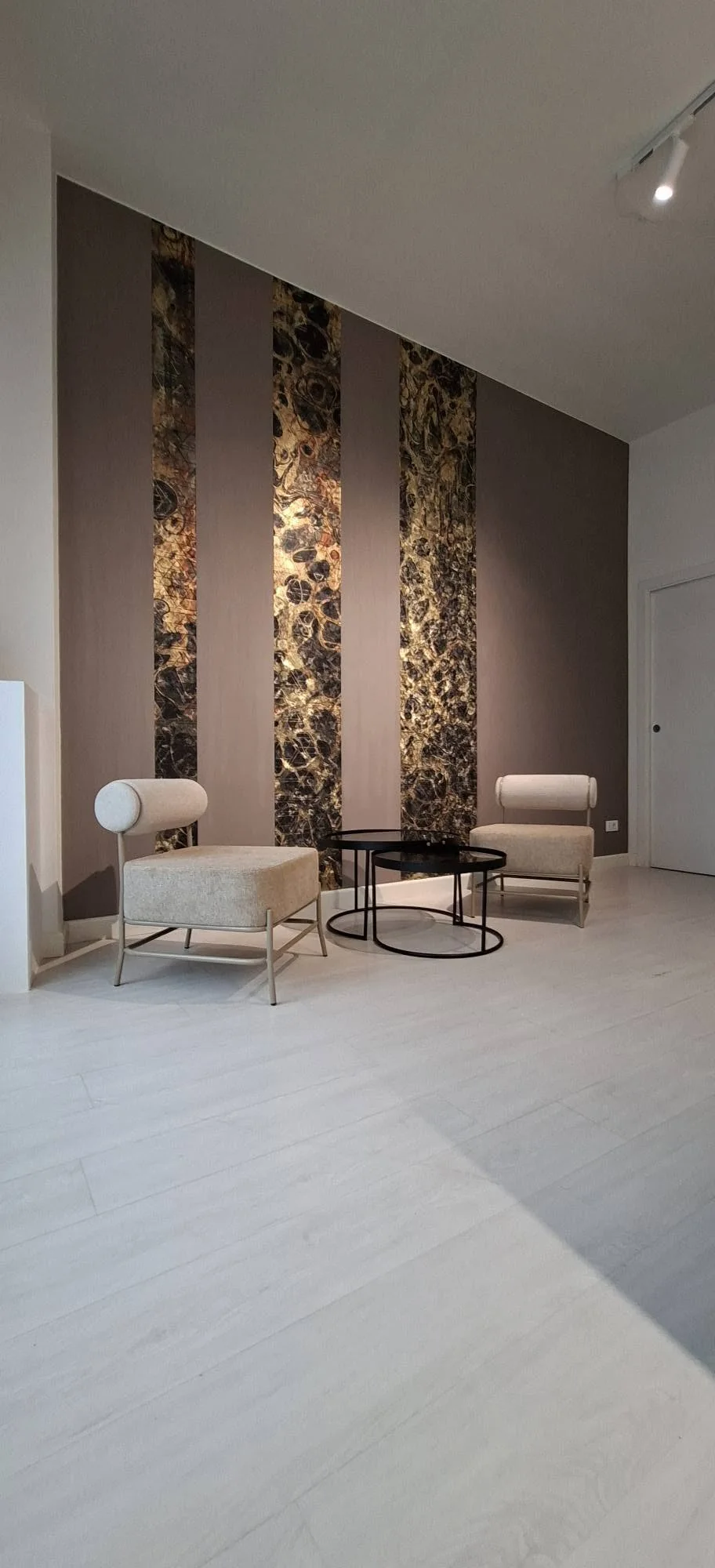 Parete con pannelli in pietra e poltroncine con tavolini